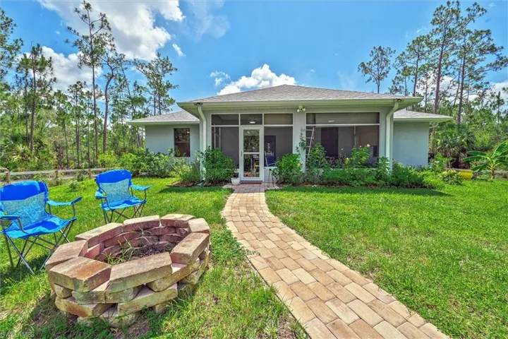 Outdoor brick fire pit and paver walkway complement the screened lanai