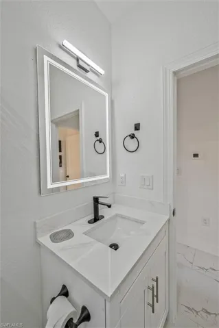 Bathroom featuring a white vanity with slab doors, integrated sink, and a black single-handle faucet