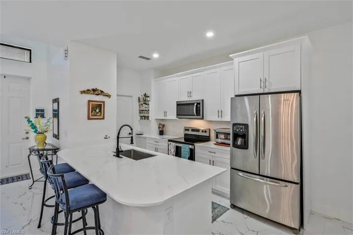 Modern kitchen featuring a large island with a quartz countertop, integrated sink, and matte black faucet