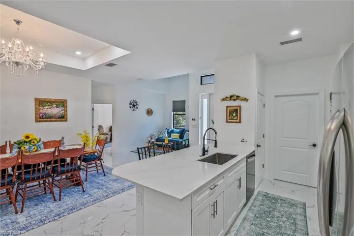 Kitchen island with a stainless steel sink and matte black faucet, white cabinetry, and a light-toned countertop