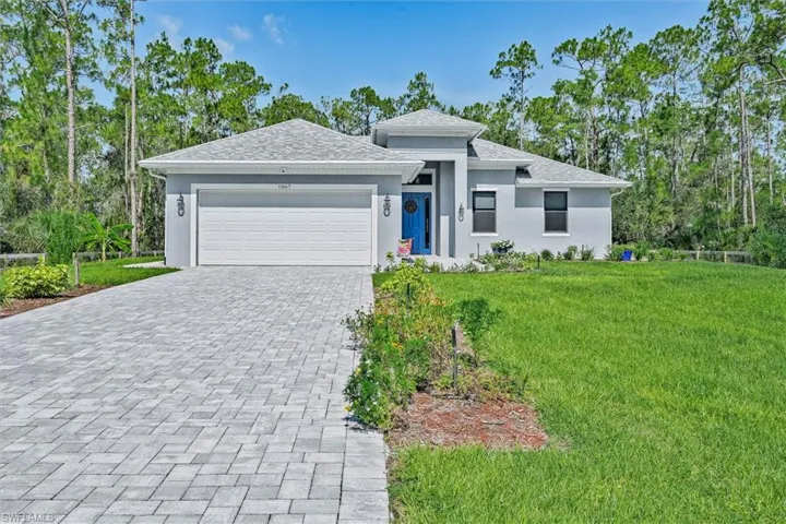 Contemporary stucco exterior with a gray palette, a distinctive blue entry door, and a paver driveway