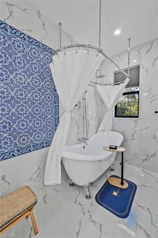 Clawfoot soaking tub with surrounding shower enclosure and rainfall showerhead