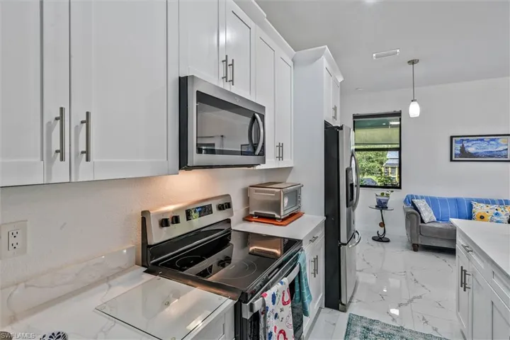Contemporary kitchen featuring white cabinetry, stainless steel appliances, and sleek countertops