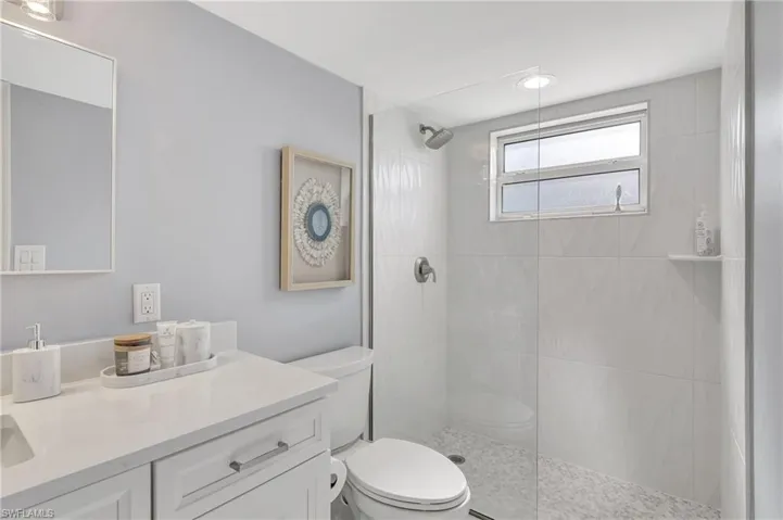 Bathroom with a tile shower, vanity, and toilet