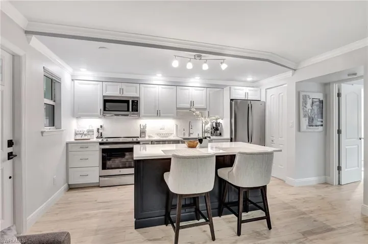 Kitchen featuring tasteful backsplash, ornamental molding, a breakfast bar, stainless steel appliances, and a center island