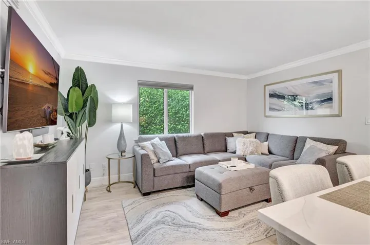 Living room with light wood-type flooring and ornamental molding
