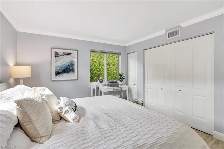 Bedroom featuring crown molding, light hardwood / wood-style floors, and two closets