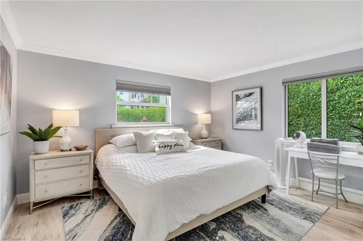 Bedroom with light wood-type flooring, crown molding, and multiple windows