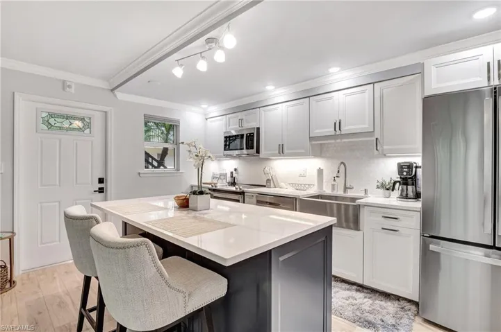 Kitchen featuring appliances with stainless steel finishes, white cabinetry, a kitchen island, and crown molding