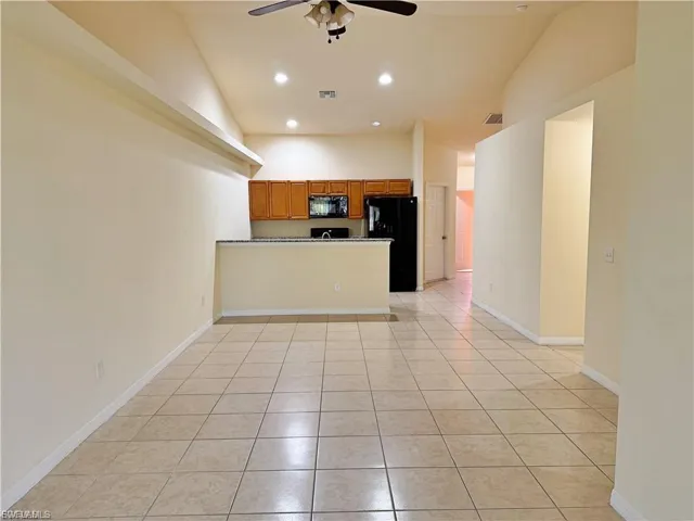 Kitchen featuring a peninsula, light tile patterned floors, brown cabinets, black appliances, and recessed lighting