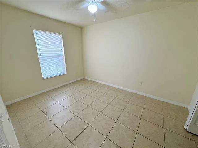 Unfurnished room featuring a textured ceiling, ceiling fan, and light tile patterned floors