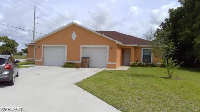 Ranch-style home featuring a front yard, stucco siding, driveway, and an attached garage