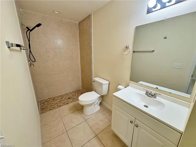 Bathroom featuring a tile shower, vanity, and light tile patterned floors
