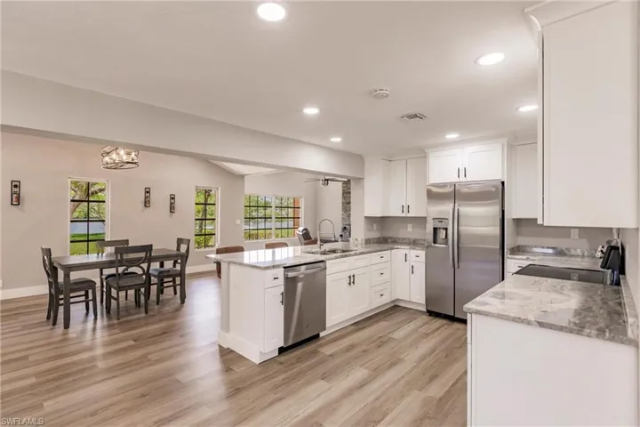 Kitchen featuring LVT / wood-style floors, white cabinets, kitchen peninsula, and stainless steel appliances