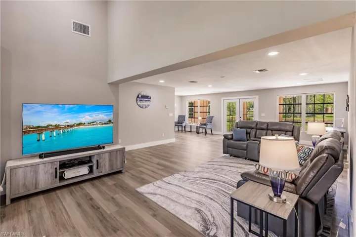 Living room featuring a high ceiling, french doors, and LVT / wood-style floors