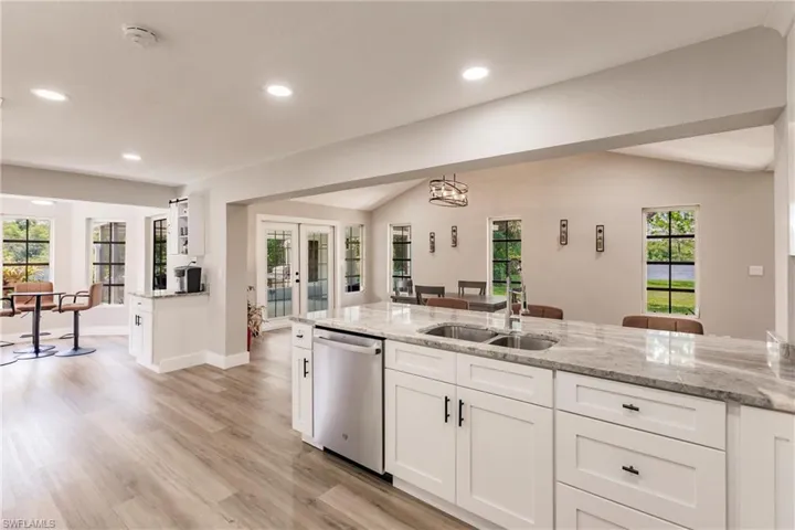Kitchen with light LVT / wood-style floors, sink, a healthy amount of sunlight, and dishwasher