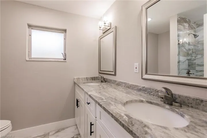 Bathroom with oversized vanity, dual sinks, toilet, and tile floors