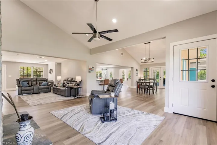 Living room featuring high vaulted ceiling, ceiling fan, light LVT / wood-style floors, and french doors