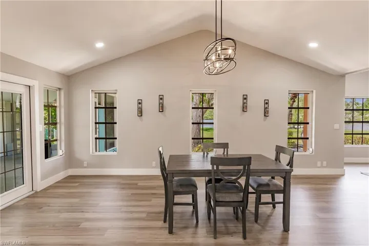 Dining room featuring high vaulted ceiling, wood-type flooring, and an inviting chandelier