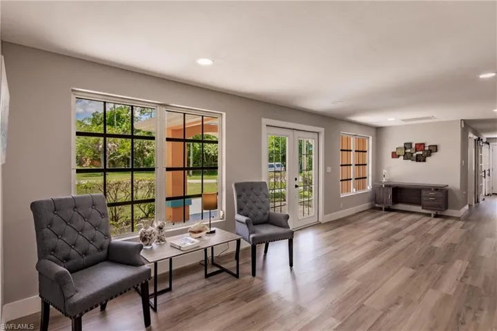 Sitting room with a healthy amount of sunlight,  LVT wood-style flooring, and french doors