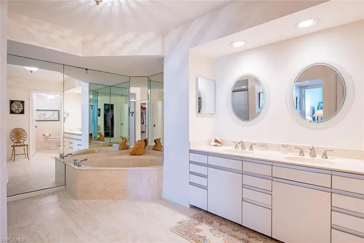 Bathroom featuring a double vanity with round mirrors and recessed lighting