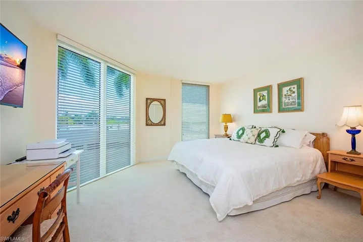 Bright interior room featuring a large sliding glass door with horizontal blinds and a secondary window