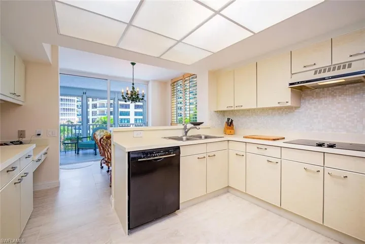 L-shaped kitchen featuring cream cabinetry, a built-in black dishwasher, and a black cooktop