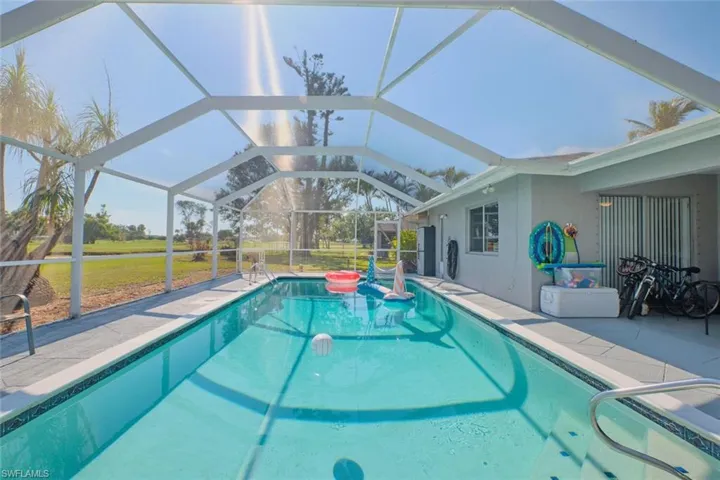 View of swimming pool featuring a patio area, a lanai, and a lawn