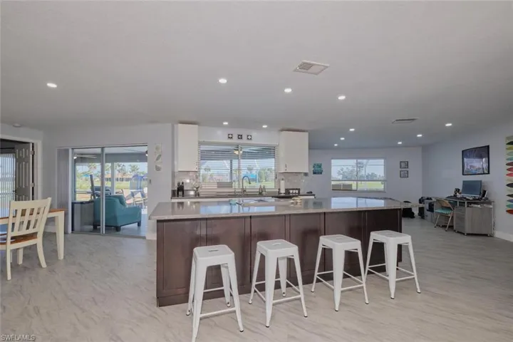 Kitchen featuring decorative backsplash, white cabinetry, a center island, and a kitchen breakfast bar