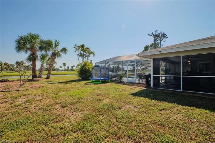 View of yard featuring a sunroom, a trampoline, and a lanai