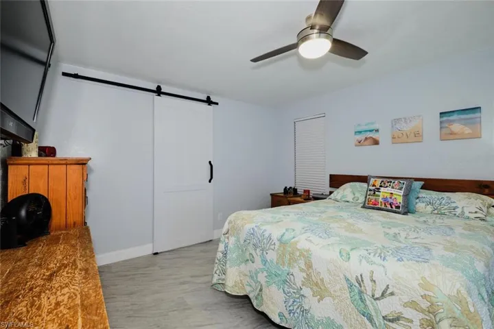 Bedroom featuring ceiling fan, light wood-type flooring, and a barn door