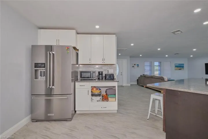 Kitchen with white cabinetry, stainless steel appliances, decorative backsplash, and a breakfast bar area
