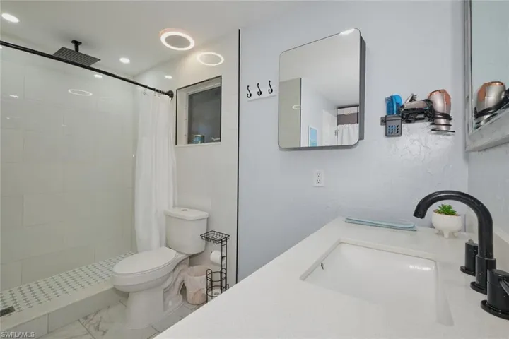 Bathroom with toilet, walk in shower, and vanity