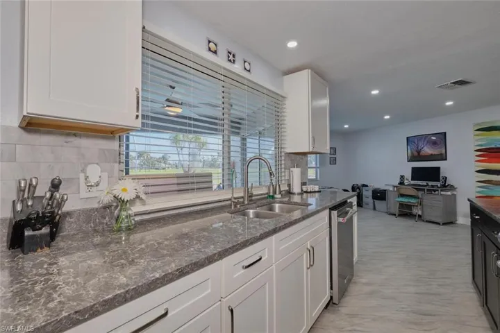 Kitchen with white cabinetry, dark stone countertops, sink, and dishwasher