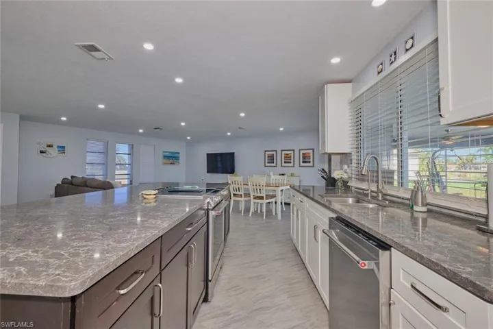 Kitchen featuring white cabinetry, dark stone counters, sink, dark brown cabinetry, and stainless steel appliances