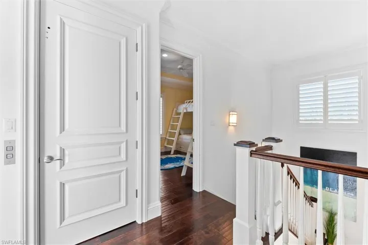 Hall with crown molding and dark wood-type flooring
