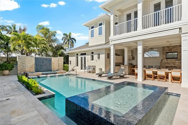 View of swimming pool featuring a bar, an outdoor hot tub, an outdoor kitchen, and a patio