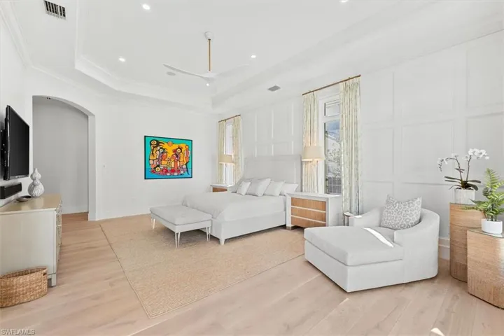 Bedroom with ornamental molding, a raised ceiling, and light hardwood / wood-style flooring