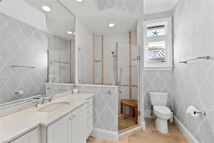 Bathroom featuring an enclosed shower, vanity, ornamental molding, and toilet