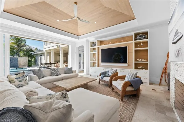 Living room featuring a raised ceiling, wooden ceiling, a fireplace, and built in shelves