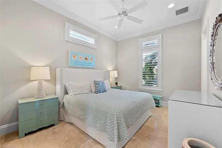 Bedroom with multiple windows, ornamental molding, and ceiling fan