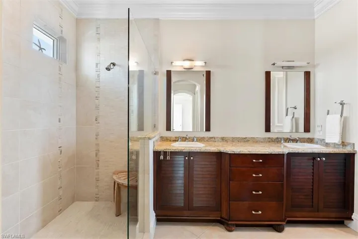 Bathroom with ornamental molding, tiled shower, vanity, and tile patterned floors