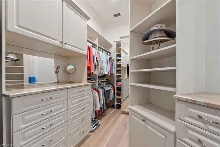 Walk in closet with light hardwood / wood-style flooring