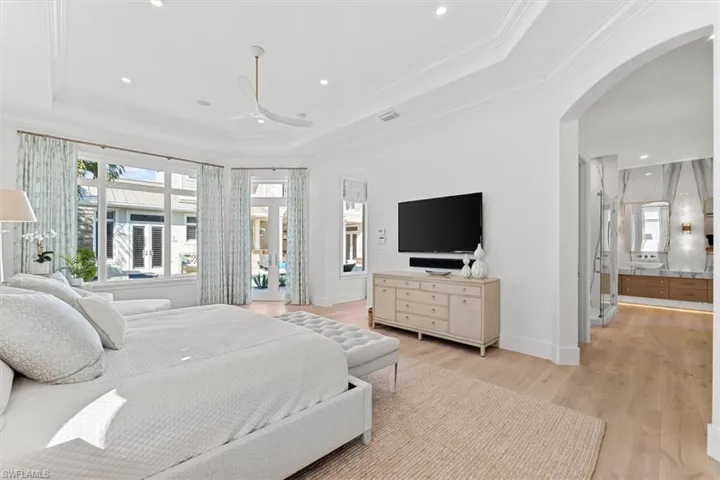 Bedroom featuring crown molding, ceiling fan, a tray ceiling, and light wood-type flooring