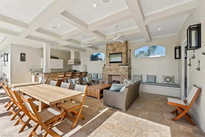 Dining space featuring coffered ceiling, ceiling fan, a fireplace, and beamed ceiling