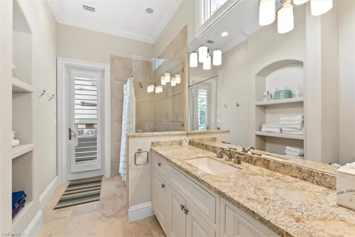 Bathroom with walk in shower, ornamental molding, built in shelves, and vanity