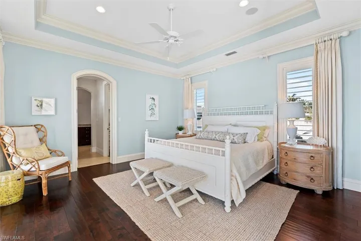 Bedroom featuring multiple windows, dark hardwood / wood-style floors, and a tray ceiling