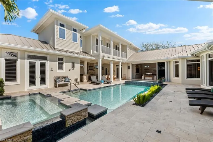 Rear view of house featuring french doors, a pool with hot tub, and a patio area