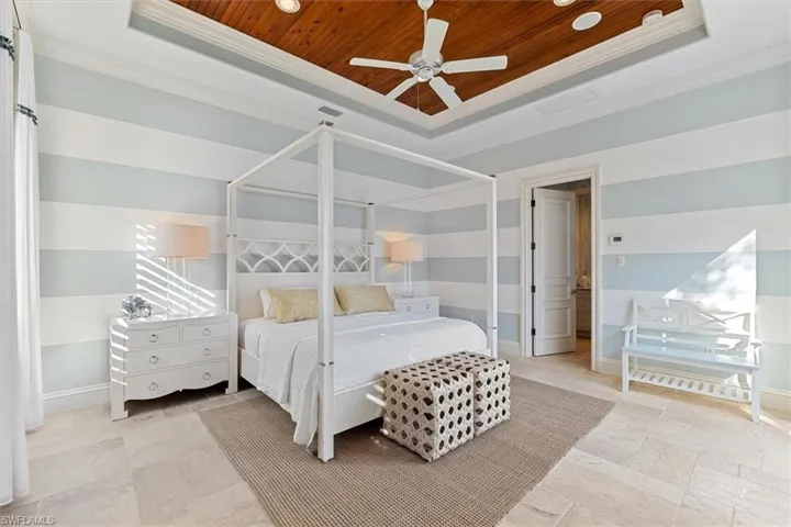 Bedroom with crown molding, wooden ceiling, ceiling fan, and a tray ceiling