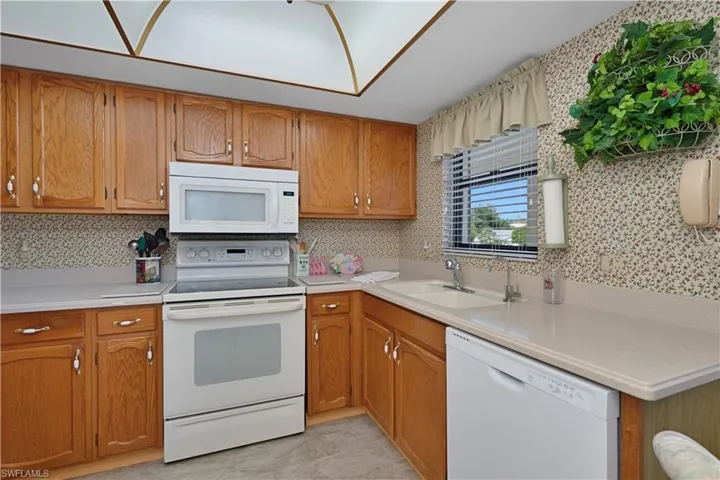 Kitchen with white appliances, light countertops, and wood cabinetry